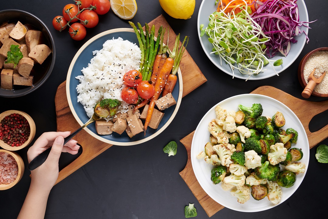 ¨Combinações: visão superior de mãos femininas segurando um bowl com vegetais variados e uma salada